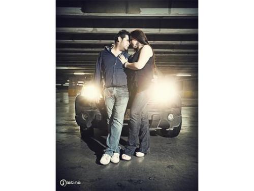 Los novios abrazándose recargados en auto con luces encendidas