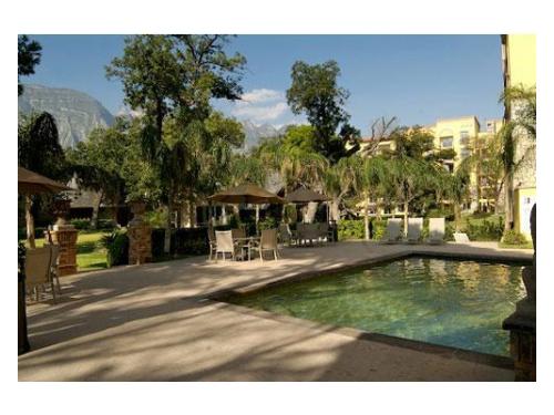 Alberca junto a mesas con sombrillas